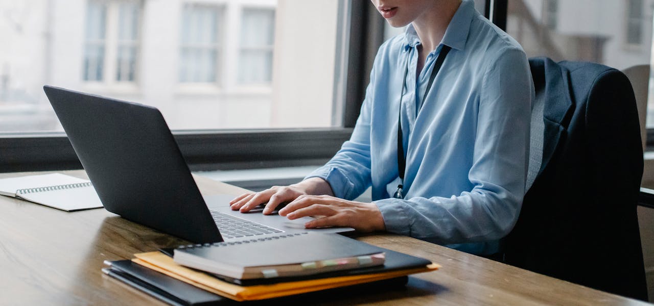 Young businesswoman working on a laptop in an office setting, demonstrating productivity and focus.